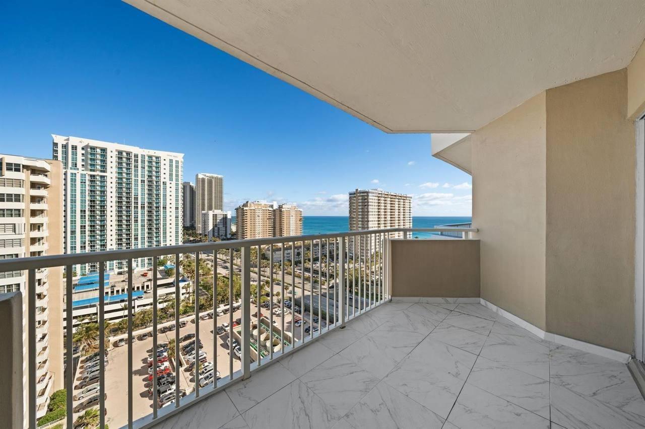 A balcony with white marble-look tile flooring overlooks a city skyline and the ocean — 1985 S Ocean Drive # 16b, Hallandale Beach FL 33009, HALLANDALE BEACH, FL