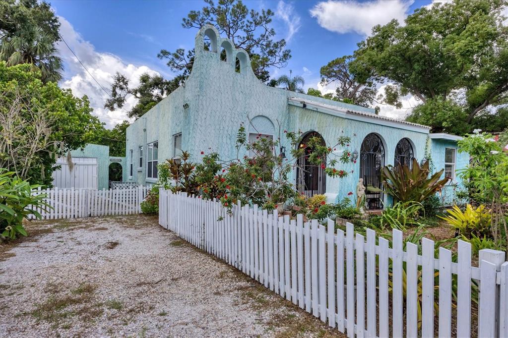 A light blue stucco house with arched entryways and a white picket fence — 1370 13TH STREET, SARASOTA, FL