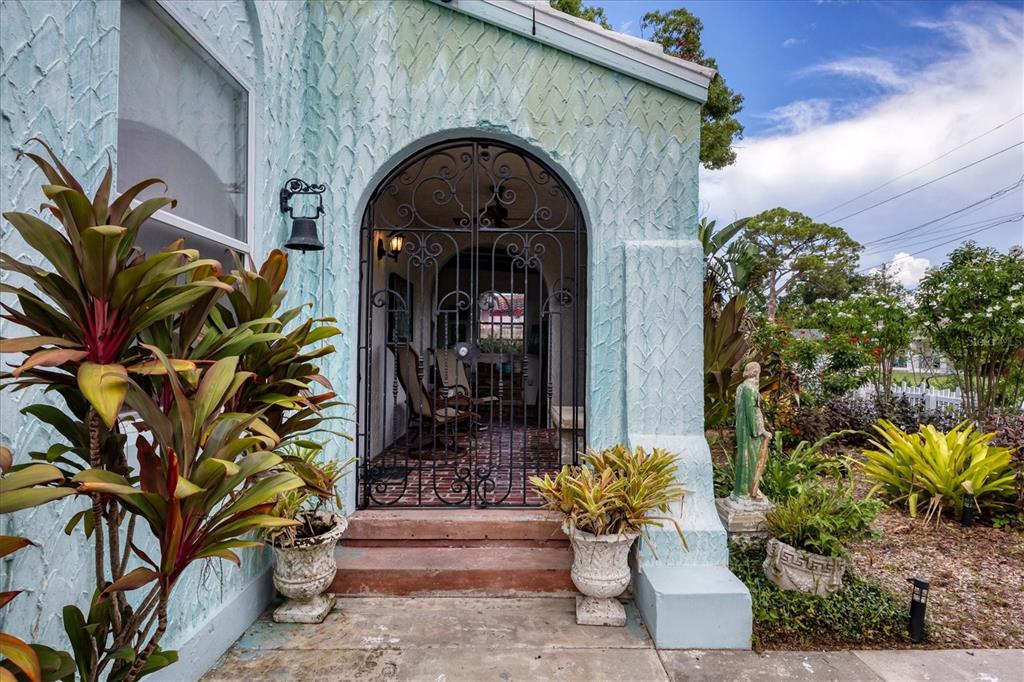 An arched entryway with a decorative iron gate leads to a covered porch — 1370 13TH STREET, SARASOTA, FL