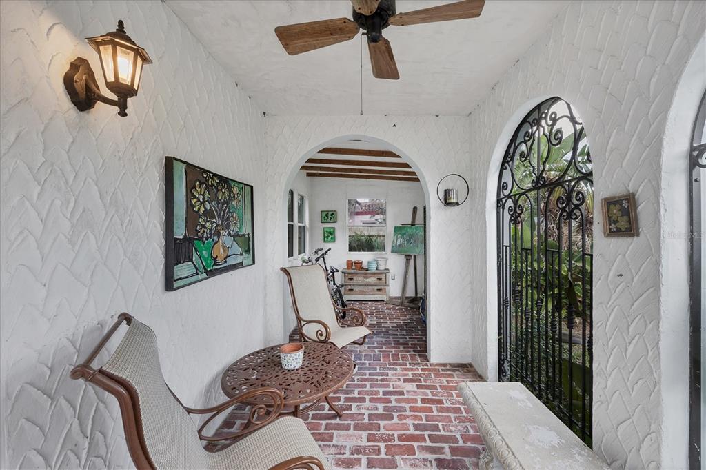 A covered porch with white textured walls, a brick floor, and an arched iron gate — 1370 13TH STREET, SARASOTA, FL