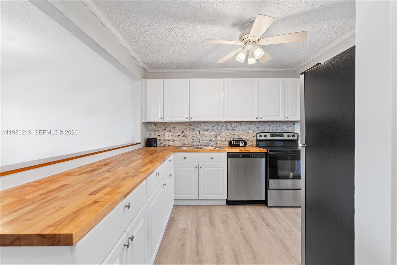 A kitchen features white cabinets, a wood countertop, stainless steel appliances, and a ceiling fan — 4800 Hillcrest Ln # 408, Hollywood FL 33021, HOLLYWOOD, FL