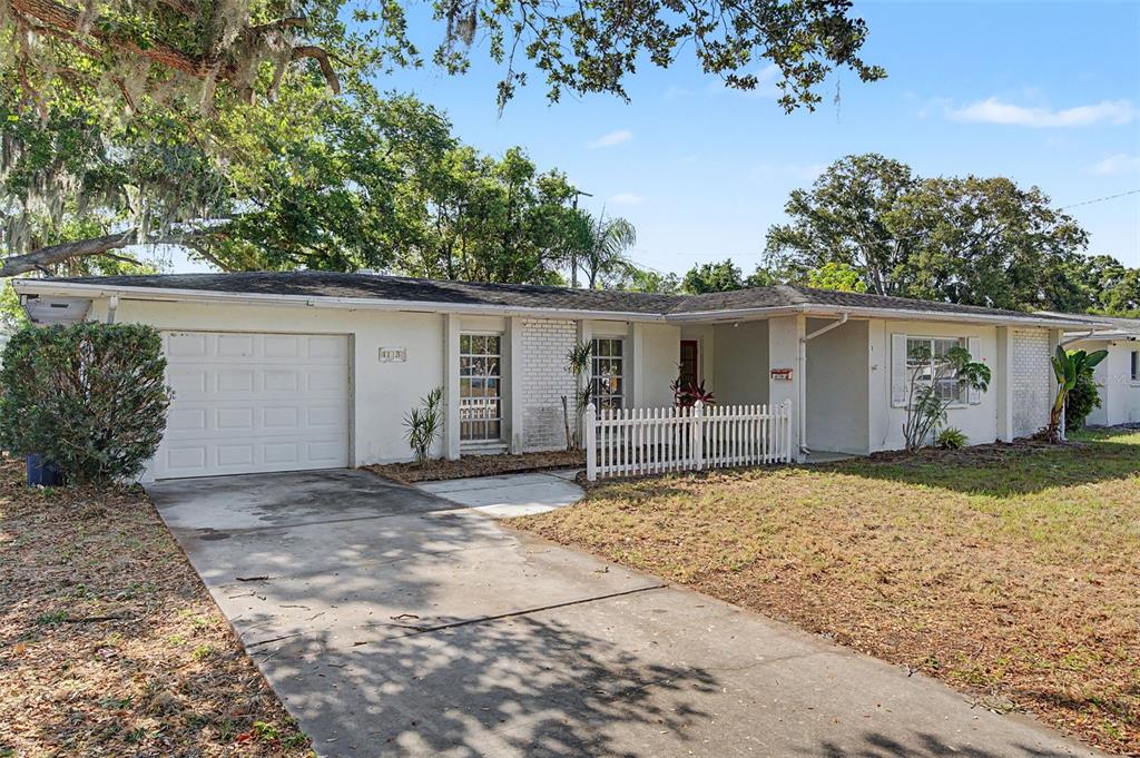 A single-story white house with a garage, a concrete driveway, and a small picket fence — 4113 PRUDENCE DRIVE, SARASOTA, FL