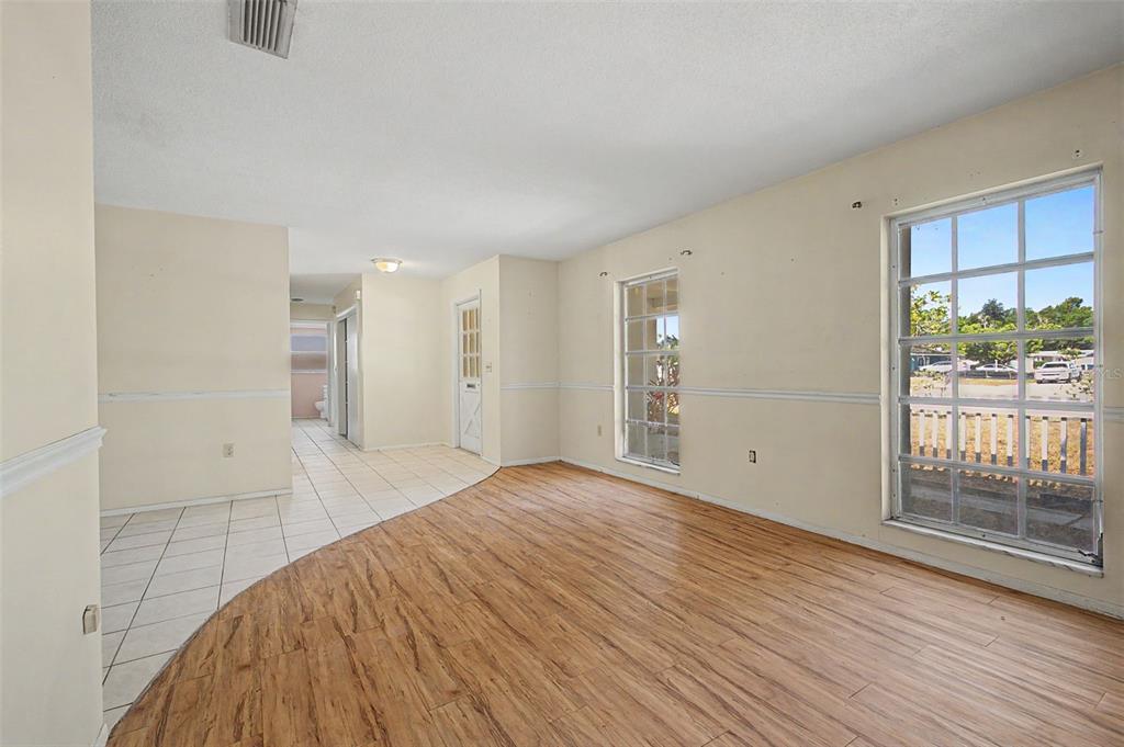 A room with a curved transition between tiled and wood-look flooring and two large windows — 4113 PRUDENCE DRIVE, SARASOTA, FL