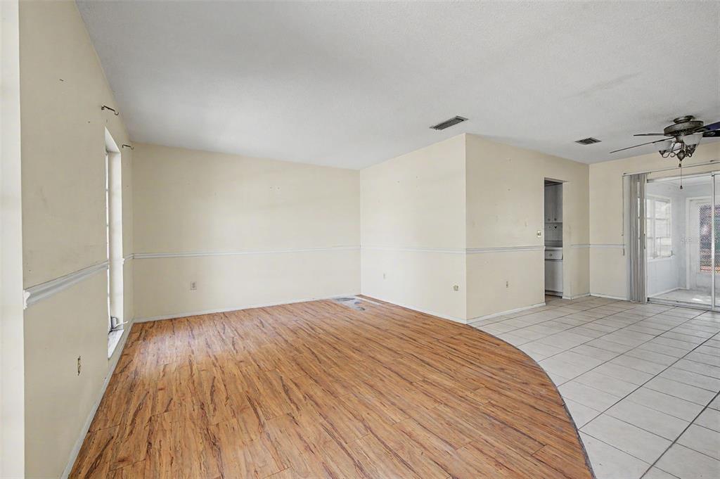 An interior view of a living area with wood-look flooring, tiled flooring, and beige walls — 4113 PRUDENCE DRIVE, SARASOTA, FL