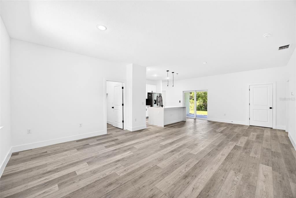 A modern living room features a grey sofa, matching armchairs, and wood-look flooring — 193 SANTA FE STREET, PORT CHARLOTTE, FL