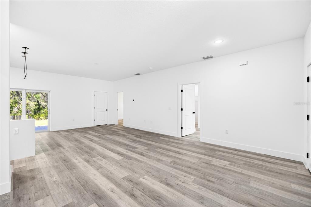 An open-concept living area features light wood-look flooring, white walls, and a kitchen island — 193 SANTA FE STREET, PORT CHARLOTTE, FL