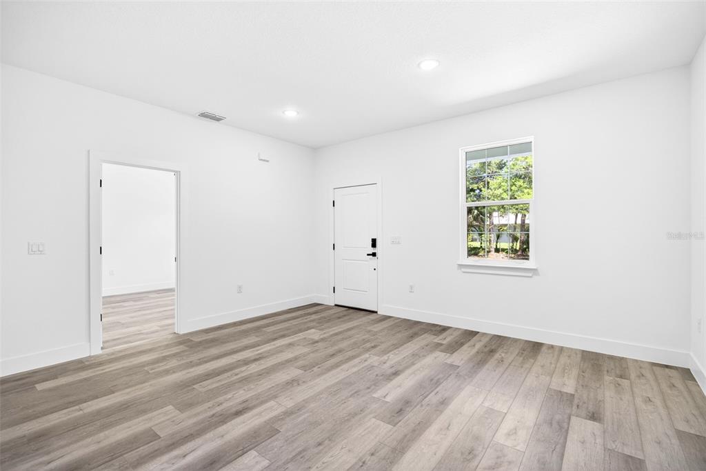 An empty room with white walls, gray wood-look flooring, and a sliding glass door — 193 SANTA FE STREET, PORT CHARLOTTE, FL