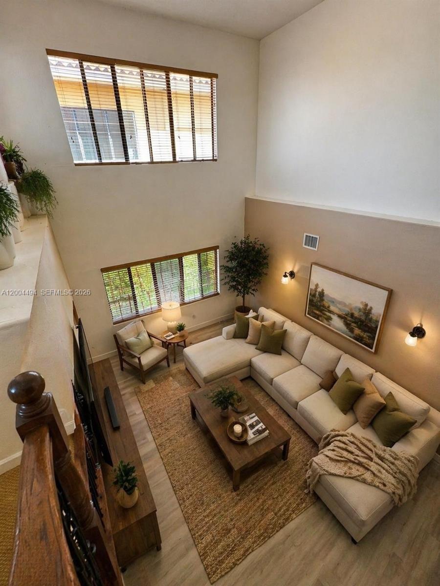 A high-ceilinged living room features a sectional sofa, a coffee table, and large windows — 7441 SW 187th St, Cutler Bay FL 33157, CUTLER BAY, FL