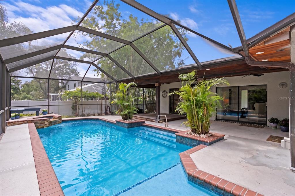 A screened-in patio features a swimming pool with a waterfall and two built-in planters — 6314 E 112TH AVENUE, TAMPA, FL
