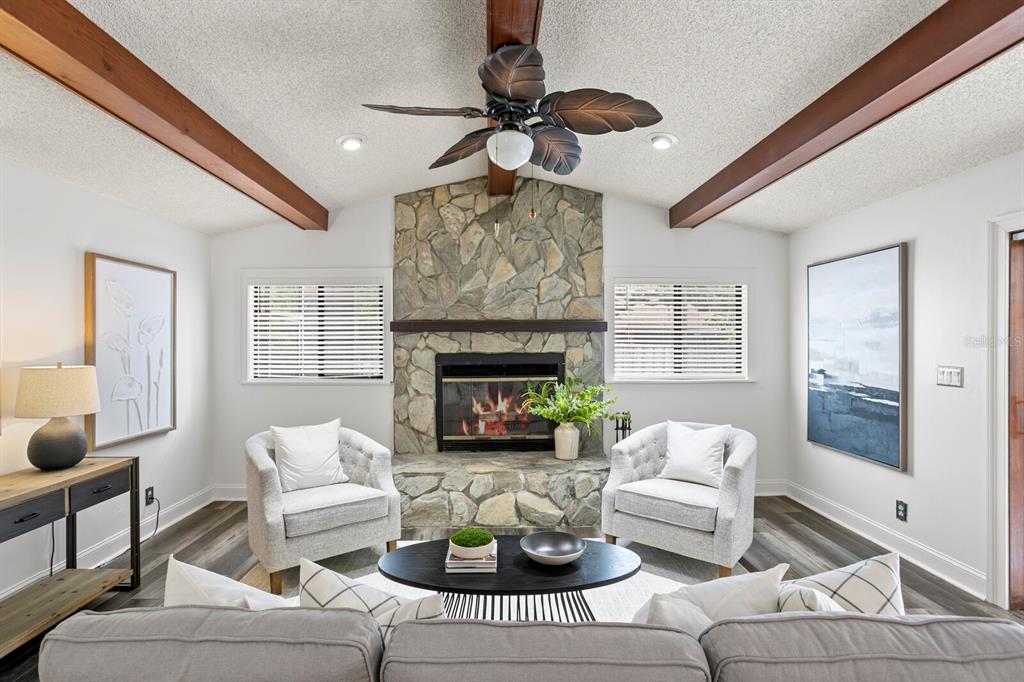 A living room features a stone fireplace, vaulted ceiling with wood beams, and two armchairs — 6314 E 112TH AVENUE, TAMPA, FL