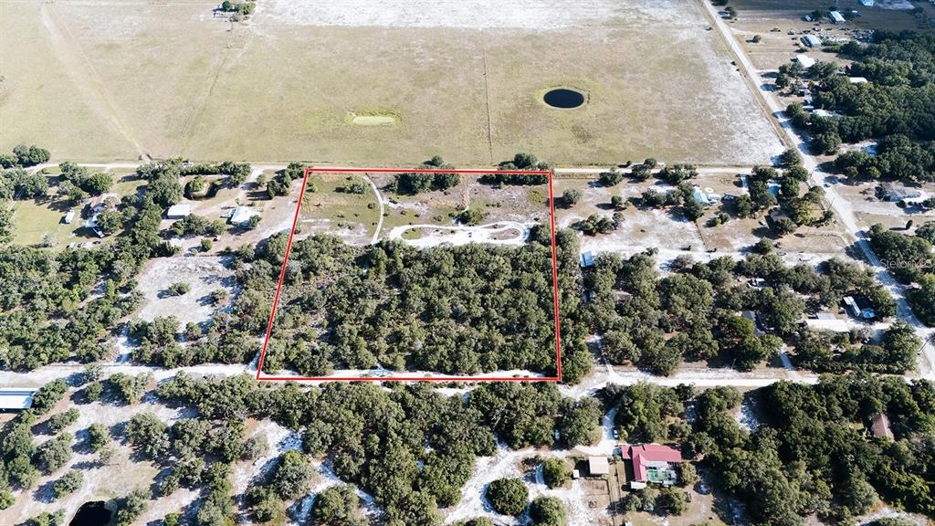 An aerial view shows a rectangular plot of land outlined in red amidst wooded surroundings — MILES BREEZE AVENUE, RIVERVIEW, FL