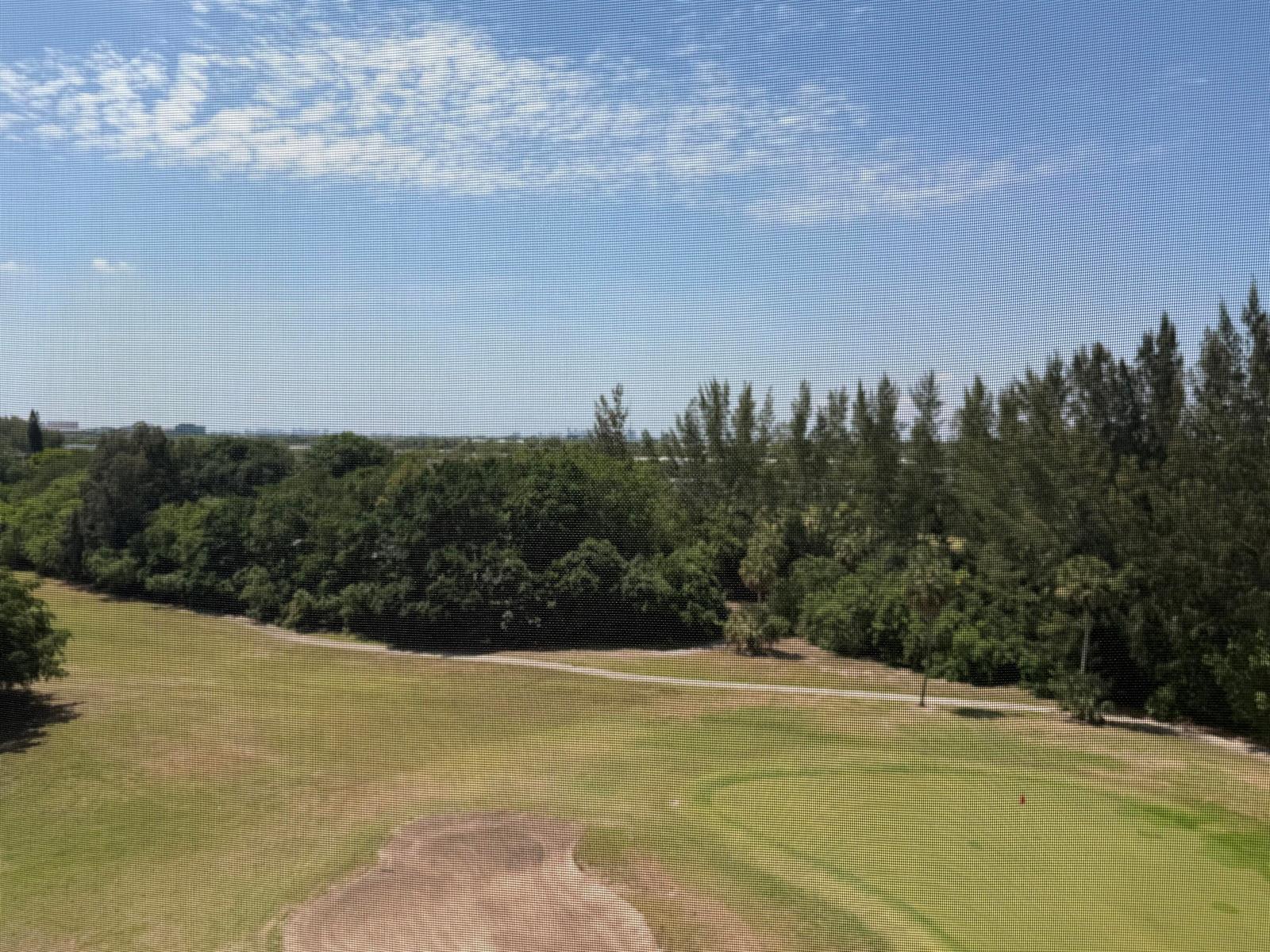 A view of a golf course fairway and surrounding trees seen through a window screen — 3150 N Palm Aire Drive # 804, Pompano Beach FL 33069, POMPANO BEACH, FL