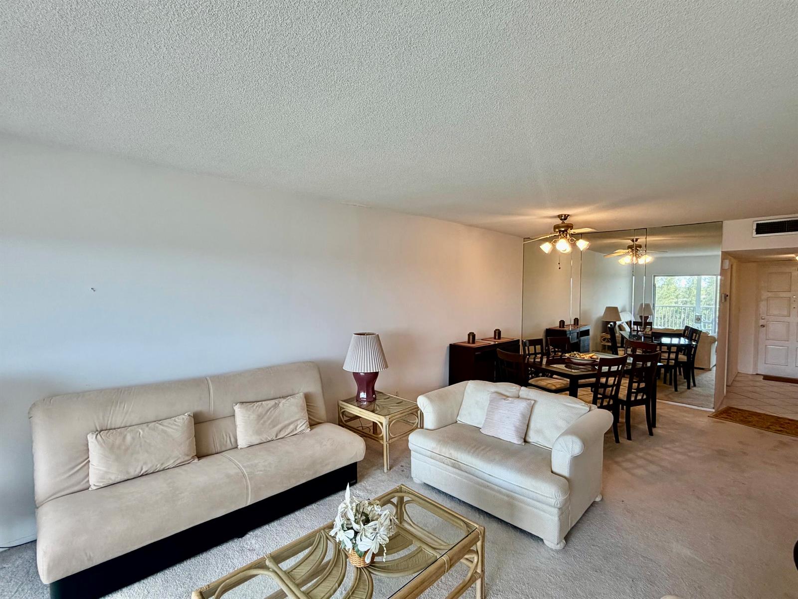A living room with beige sofas, a glass-topped coffee table, and a mirrored dining area — 3150 N Palm Aire Drive # 804, Pompano Beach FL 33069, POMPANO BEACH, FL