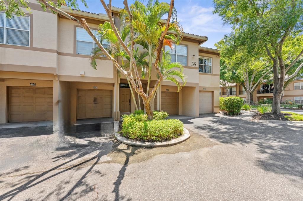 A multi-unit residential building with tan stucco walls, brown garage doors, and a palm tree — 603 ARBOR LAKE LN, TAMPA, FL