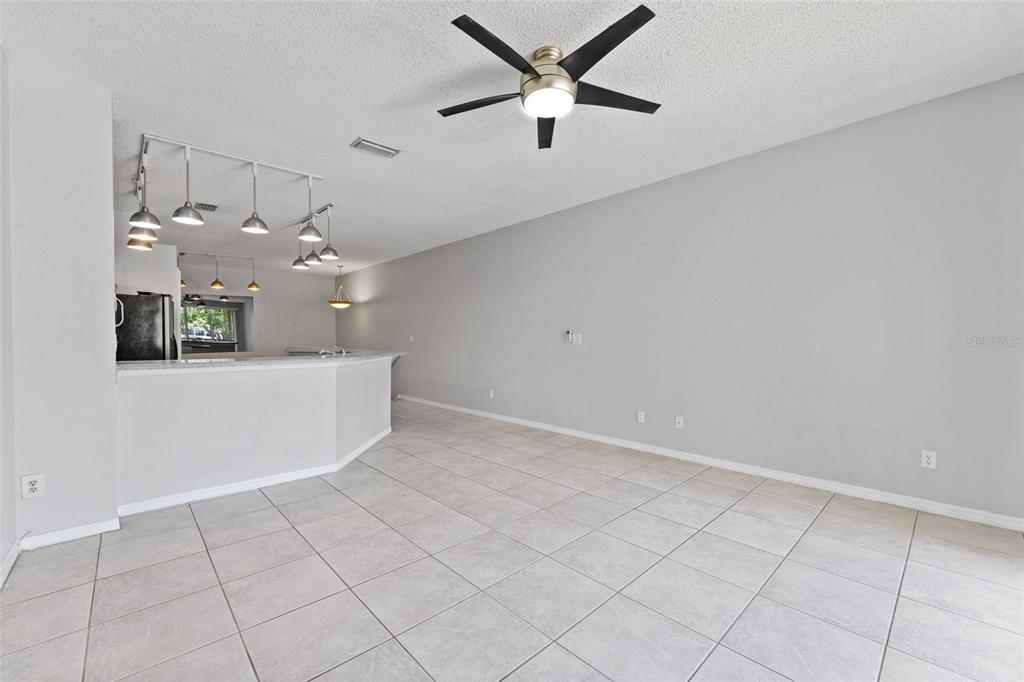 A living area with tile flooring, a ceiling fan, and a kitchen breakfast bar — 603 ARBOR LAKE LN, TAMPA, FL