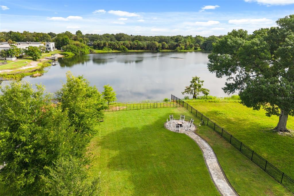 An aerial view shows a grassy backyard with a stone patio, fire pit, and lake — 4401 PARK LAKE STREET, ORLANDO, FL