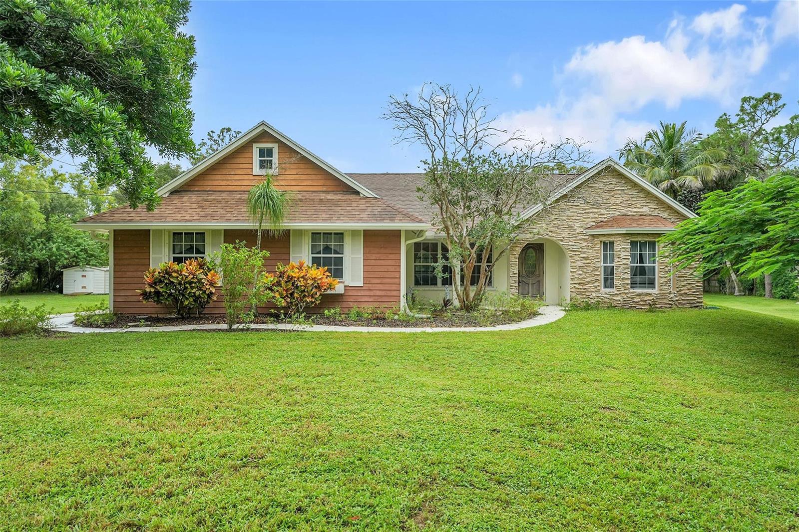 A single-story house with wood siding, stone veneer, and a large front lawn — 18392 48th Avenue N, Loxahatchee FL 33470, LOXAHATCHEE, FL