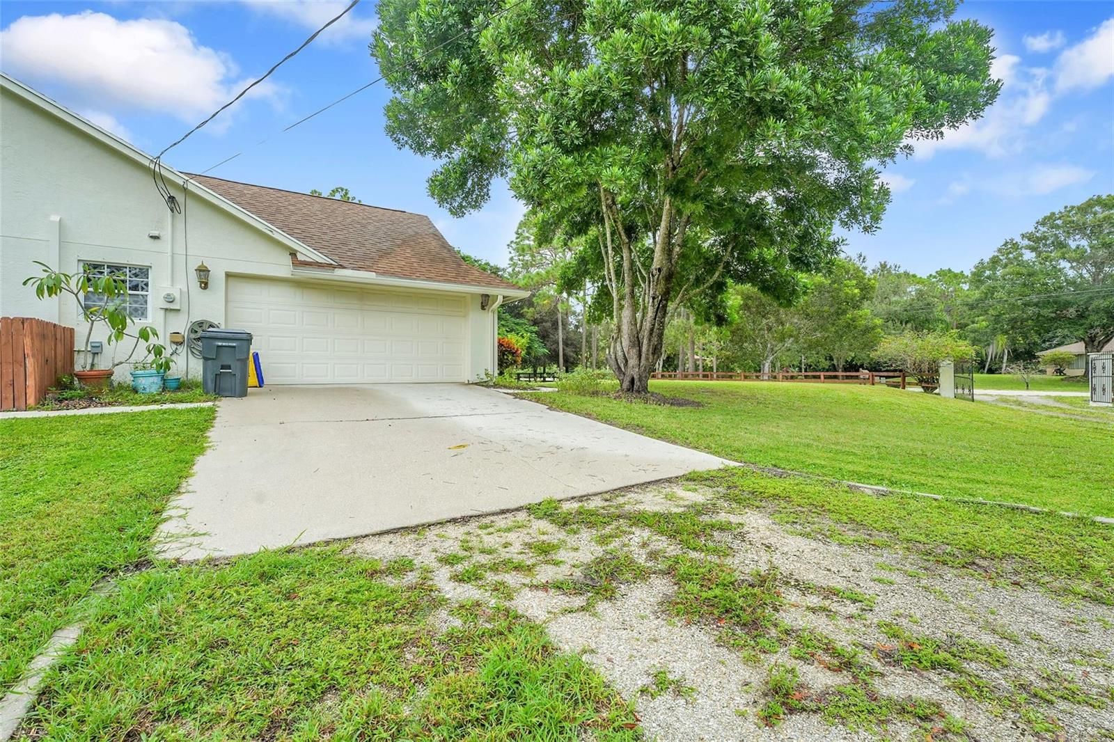 A concrete driveway leads to a two-car garage attached to a house with a large tree — 18392 48th Avenue N, Loxahatchee FL 33470, LOXAHATCHEE, FL