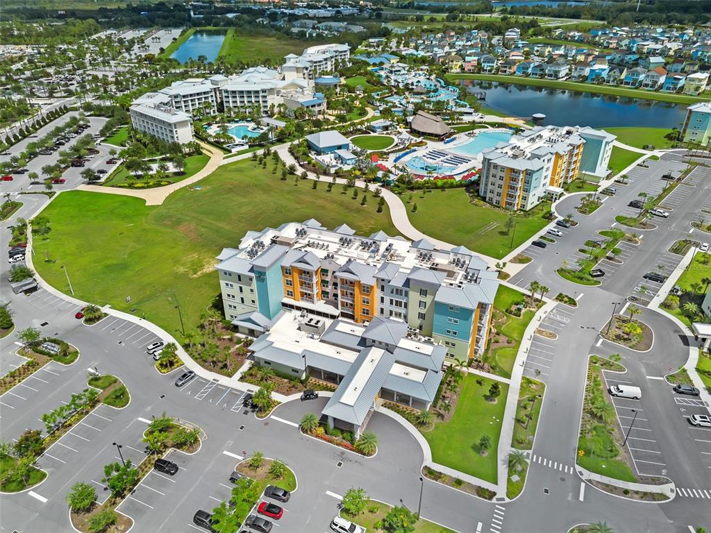 An aerial view shows a large hotel complex with swimming pools, parking lots, and landscaping — 8070 UNWIND WAY UNIT 5211, KISSIMMEE, FL