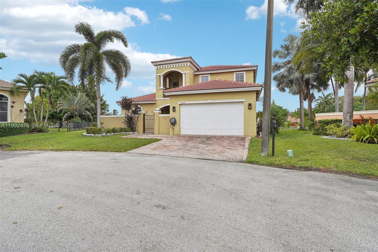 A two-story yellow stucco house with a red tile roof and a two-car garage — 13247 SW 26th St, Miramar FL 33027, MIRAMAR, FL