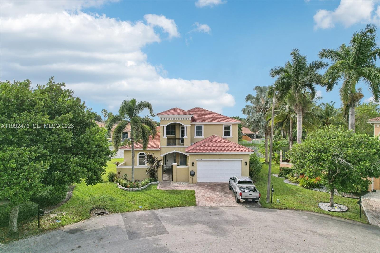 A two-story house with a red tile roof and a white garage sits on a lawn — 13247 SW 26th St, Miramar FL 33027, MIRAMAR, FL