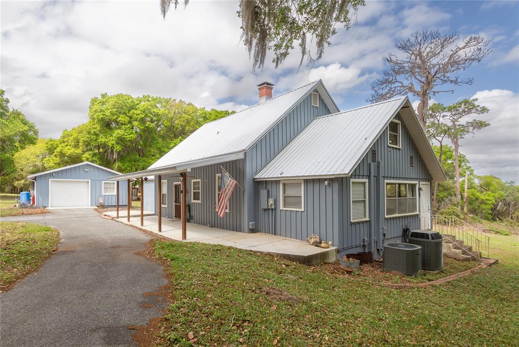 A blue house with a metal roof and a detached garage sits on a grassy lot — 1905 MYRTLE LAKE AVENUE, FRUITLAND PARK, FL