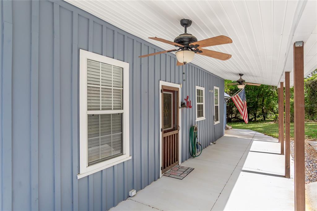 A blue board-and-batten house features a covered porch with ceiling fans and an American flag — 1905 MYRTLE LAKE AVENUE, FRUITLAND PARK, FL