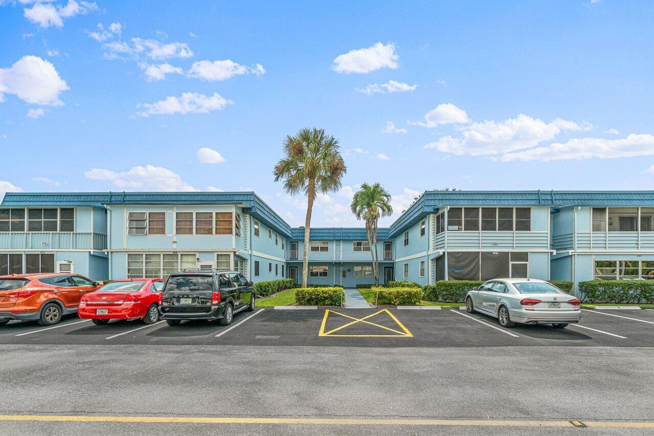 A two-story blue apartment building with a parking lot in the foreground — 260 Brittany F, Delray Beach FL 33446, DELRAY BEACH, FL