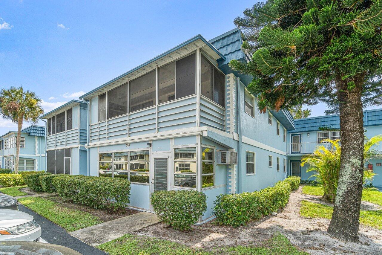 A two-story blue apartment building with a screened-in balcony and surrounding landscaping — 260 Brittany F, Delray Beach FL 33446, DELRAY BEACH, FL