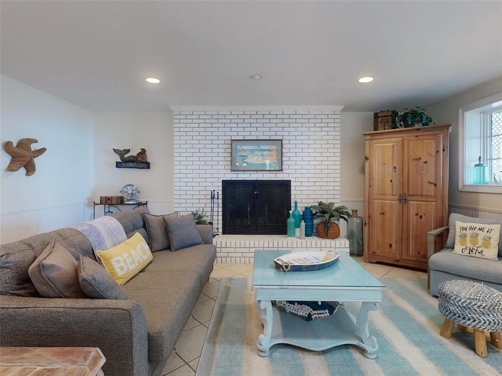 A living room features a white brick fireplace, a grey sofa, and a light blue table — 1913 HILL STREET UNIT 1, NEW SMYRNA BEACH, FL