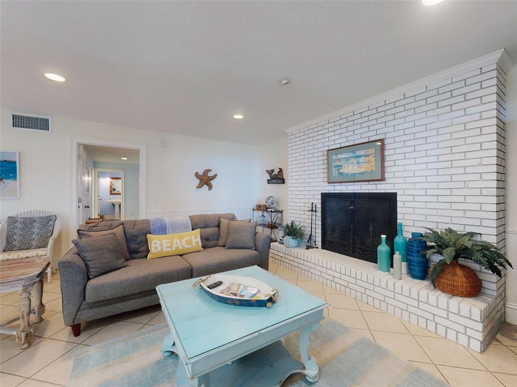 A living room features a white brick fireplace, a gray sofa, and a light blue table — 1913 HILL STREET UNIT 1, NEW SMYRNA BEACH, FL