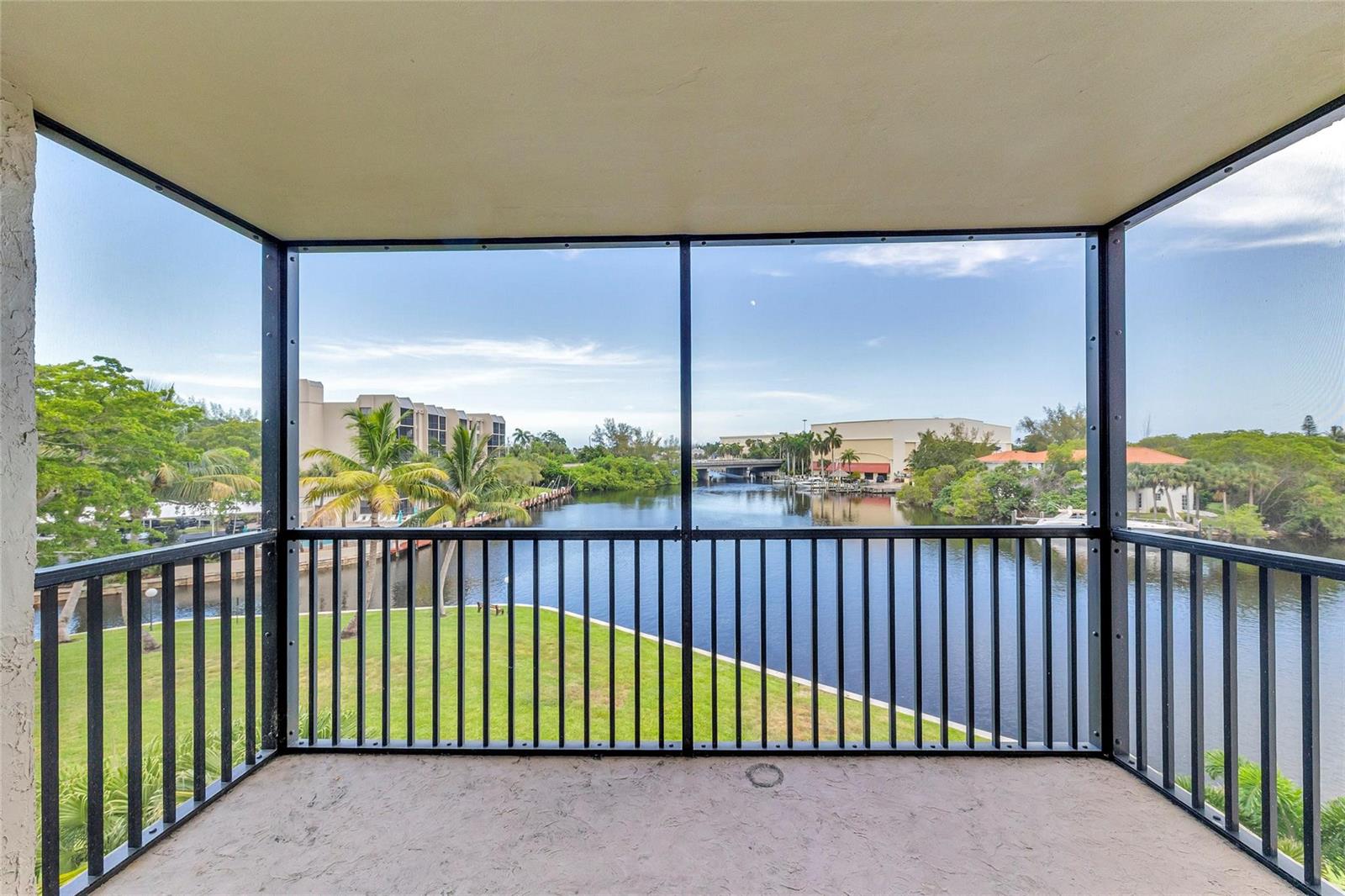 A screened-in balcony overlooks a canal with green lawns and distant buildings — 7 Royal Palm Way, Boca Raton FL 33432, BOCA RATON, FL