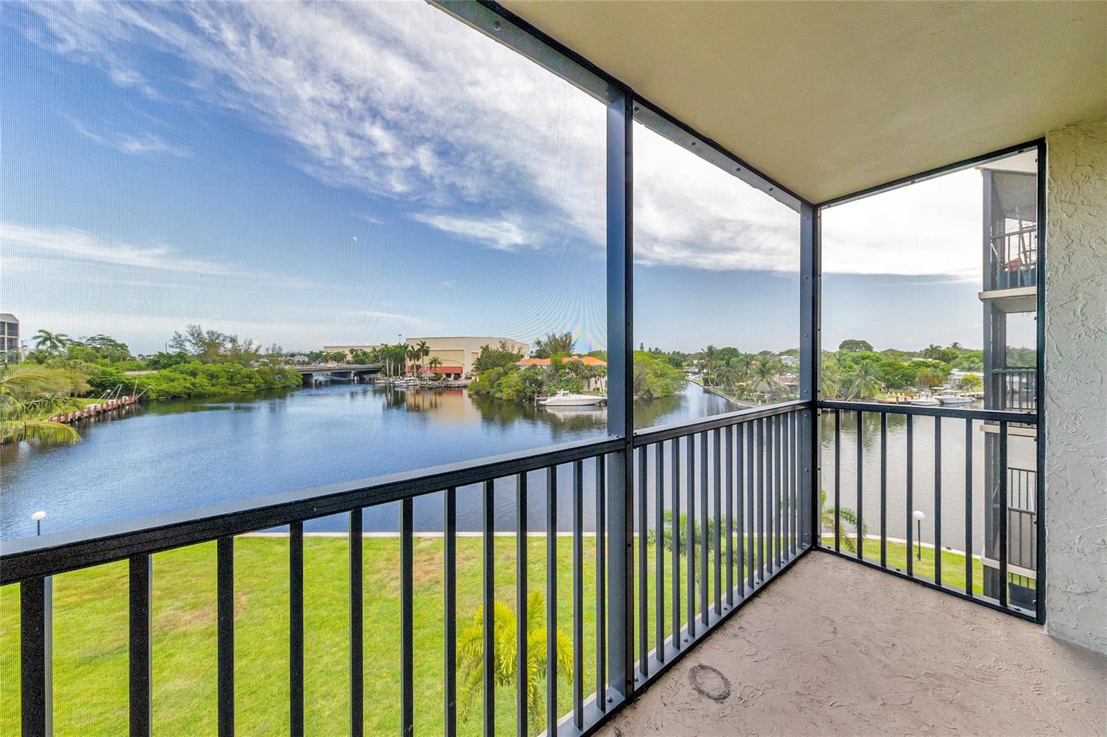 A screened-in balcony overlooks a calm canal with green lawns and distant buildings — 7 Royal Palm Way, Boca Raton FL 33432, BOCA RATON, FL