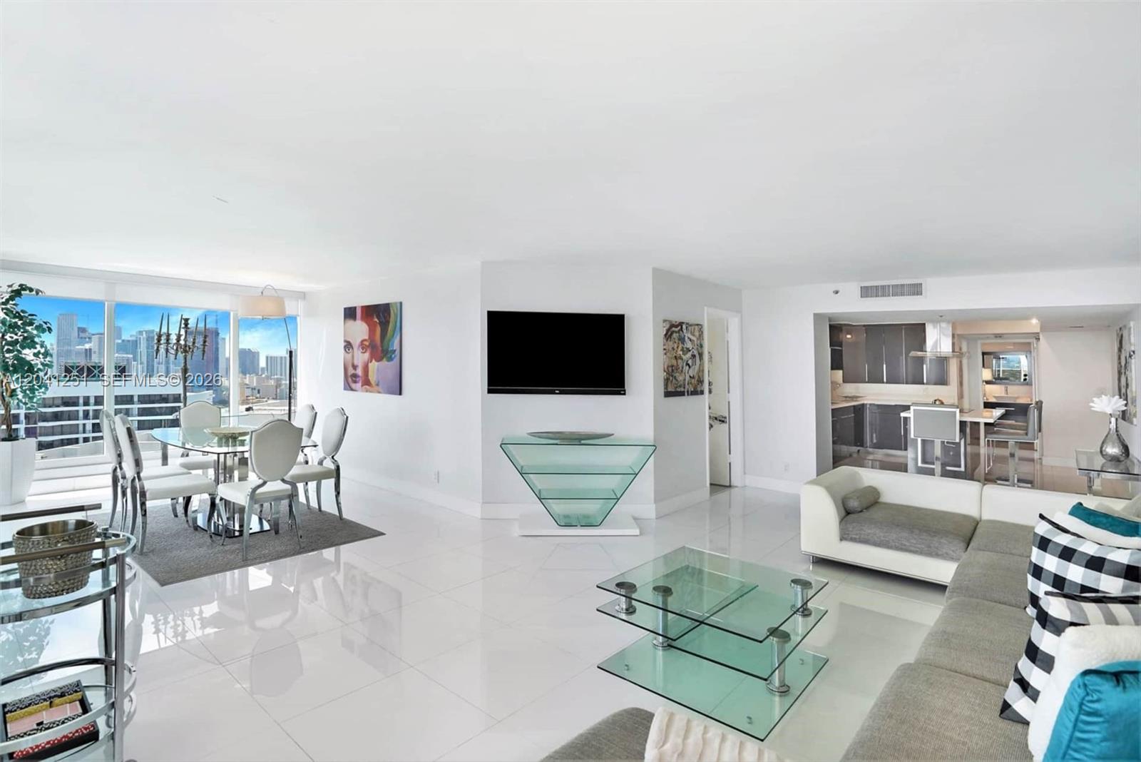A bright, open-concept living and dining area features white tile floors and city skyline views — 1717 N Bayshore Dr # 3931, Miami FL 33132, MIAMI, FL