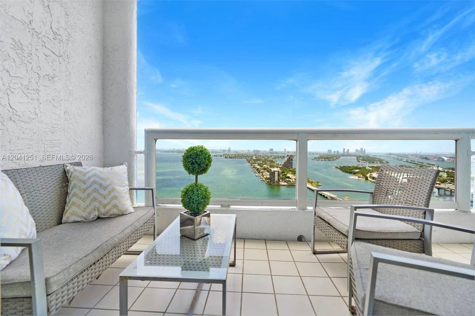 A balcony with outdoor seating overlooks a bay and a city skyline — 1717 N Bayshore Dr # 3931, Miami FL 33132, MIAMI, FL