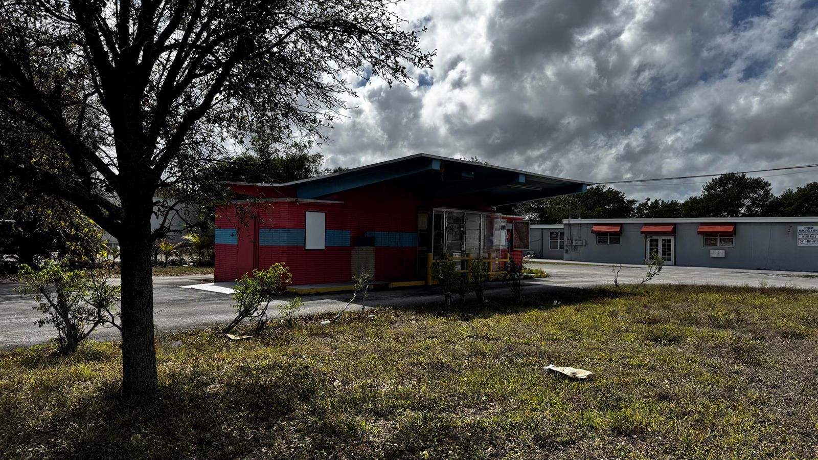 A red and blue commercial building with a drive-thru canopy stands on a paved lot — 3263 Sierra Drive, Palm Springs FL 33461, PALM SPRINGS, FL