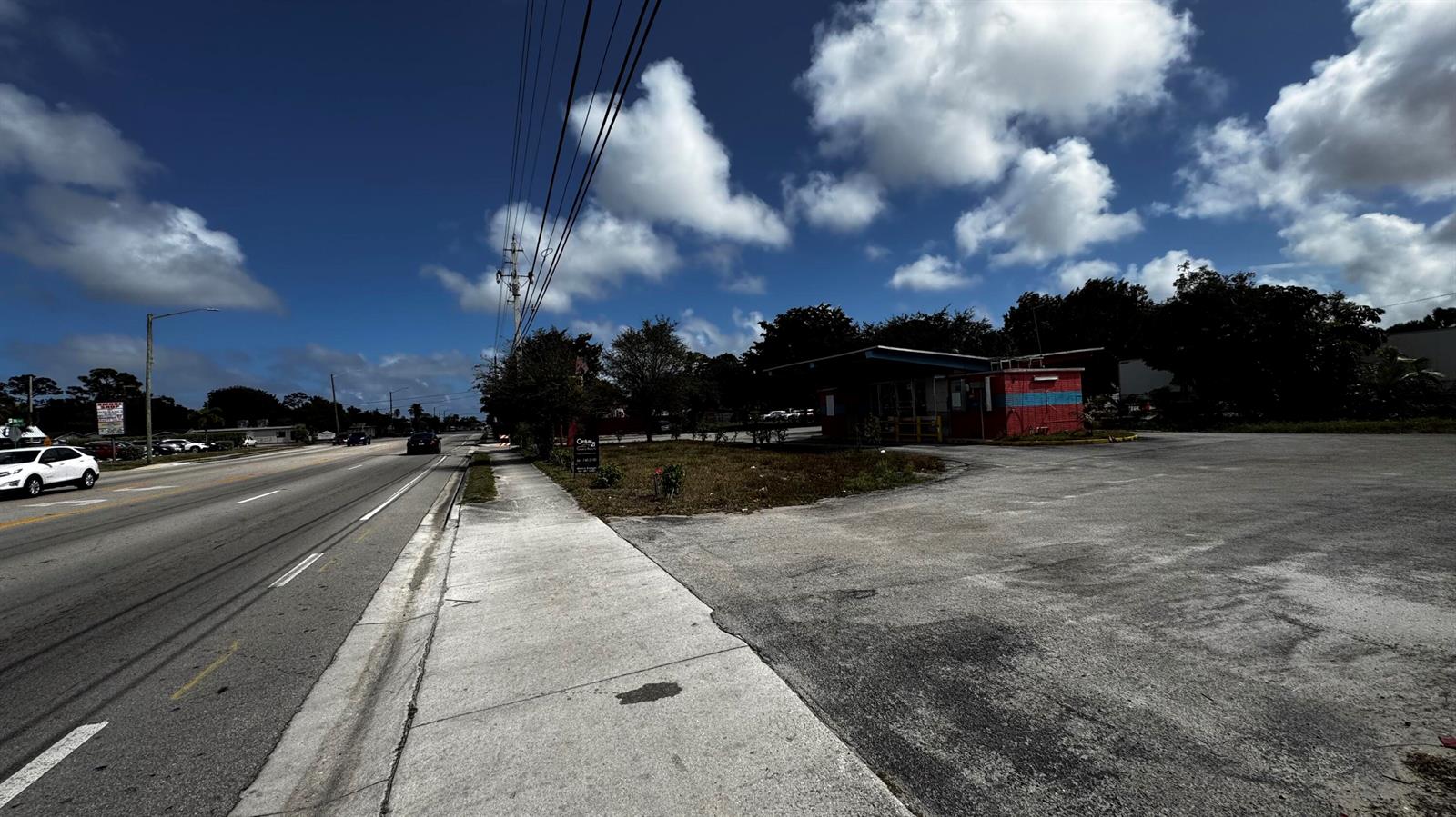 A roadside commercial building with a red and blue exterior sits beside a paved road — 3263 Sierra Drive, Palm Springs FL 33461, PALM SPRINGS, FL