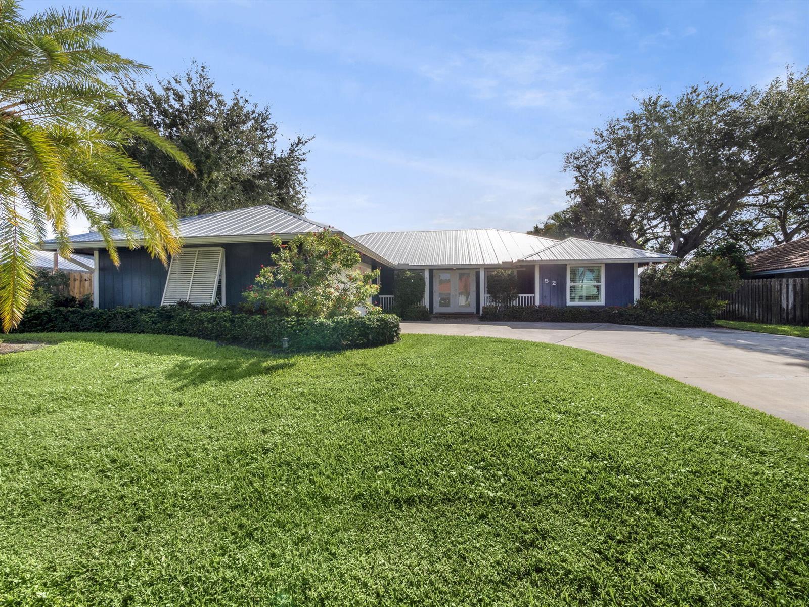 A blue single-story house with a metal roof and a large front lawn — 52 Birch Place, Tequesta FL 33469, TEQUESTA, FL