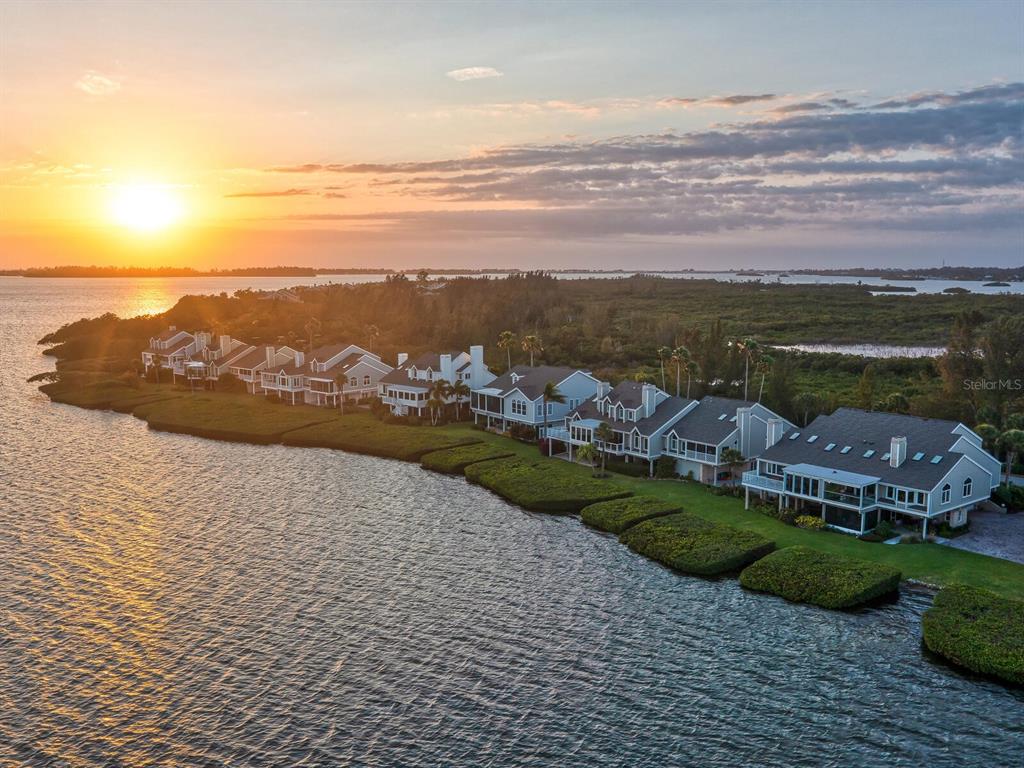 An aerial view of waterfront houses along a grassy shoreline at sunset — 26 TIDY ISLAND BOULEVARD, BRADENTON, FL