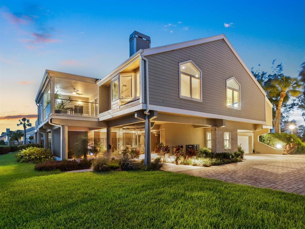A two-story house with beige siding, a raised ground level, and a paved driveway — 26 TIDY ISLAND BOULEVARD, BRADENTON, FL