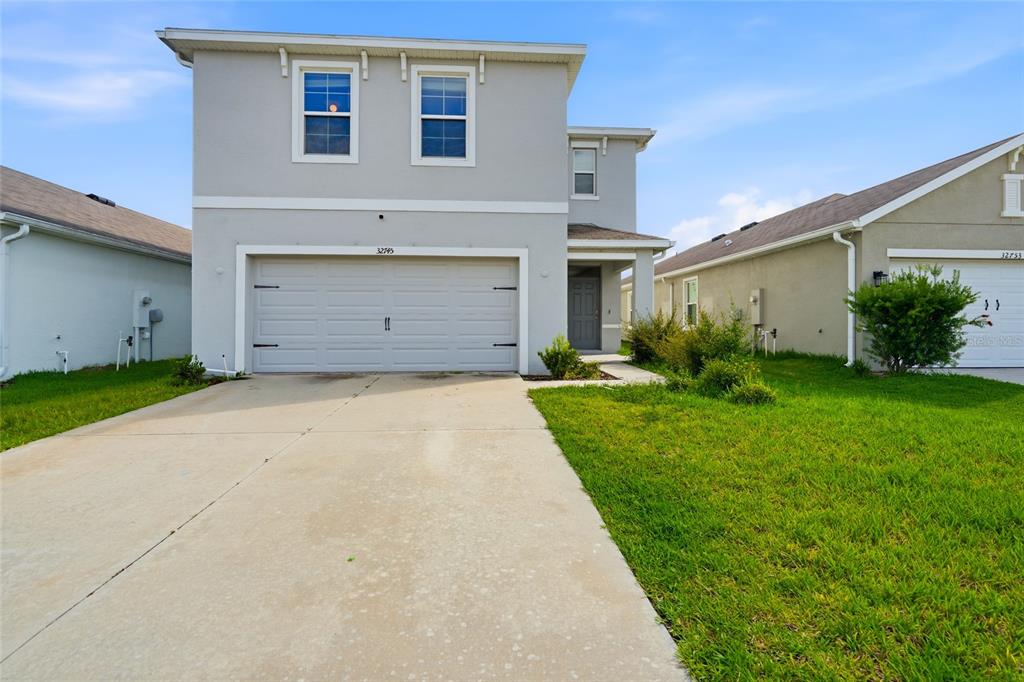 A two-story suburban house with a gray exterior, a two-car garage, and a concrete driveway — 32745 PEZ LANDING LANE, WESLEY CHAPEL, FL