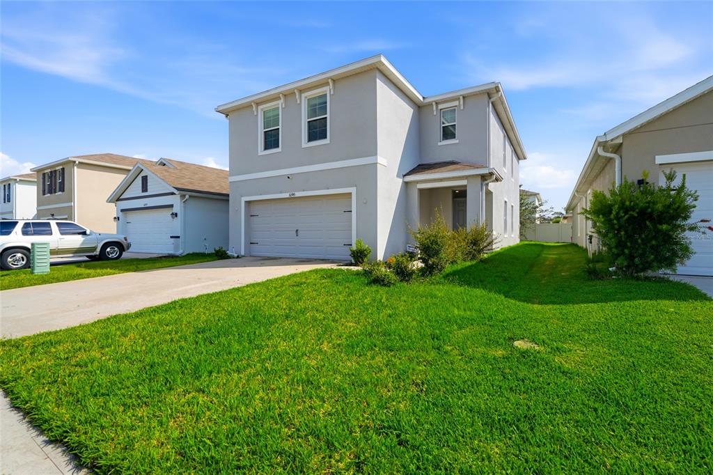 A two-story light gray house with a two-car garage and a green lawn — 32745 PEZ LANDING LANE, WESLEY CHAPEL, FL