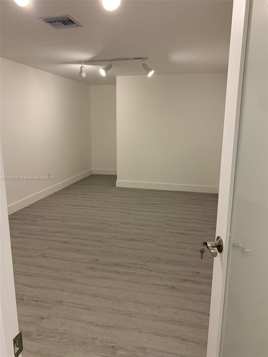 This room features light wood-look flooring, white walls, and adjustable track lighting on the ceiling — 638 NW 62nd St, Miami FL 33150, MIAMI, FL