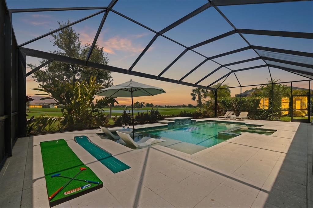 A screened-in pool patio features a putting green game, lounge chairs, and golf course views — 14817 MONTELLO WAY, BRADENTON, FL