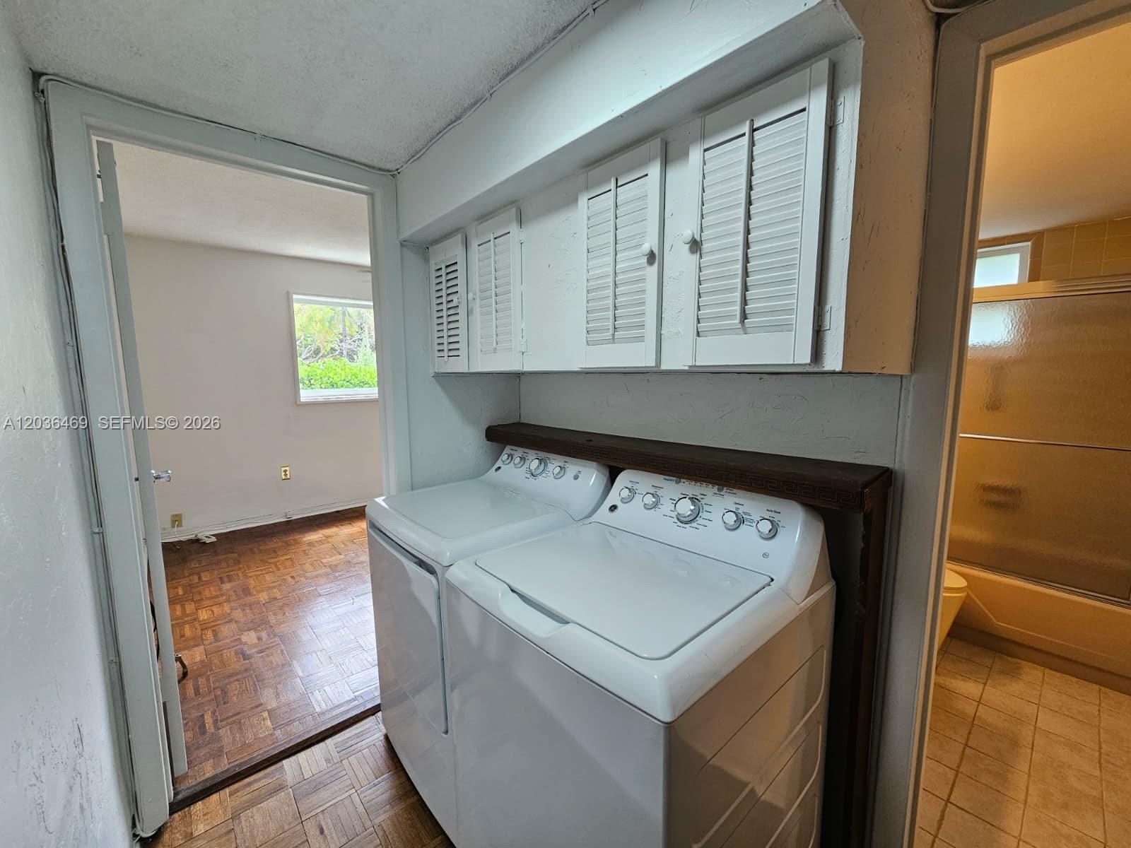A laundry area features white appliances beneath wooden cabinets and a dark shelf — 520 NE 38th St # 12, Miami FL 33137, MIAMI, FL