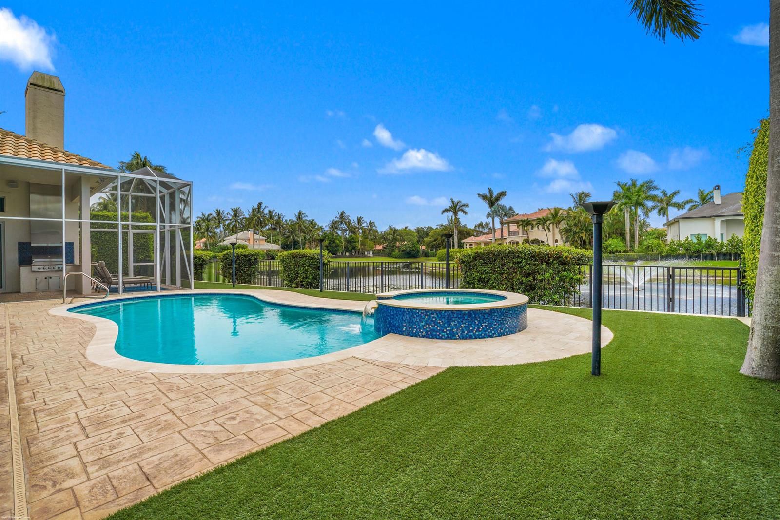 A backyard features a swimming pool, a tiled hot tub, and a patio overlooking a lake — 12809 Mizner Way, Wellington FL 33414, WELLINGTON, FL