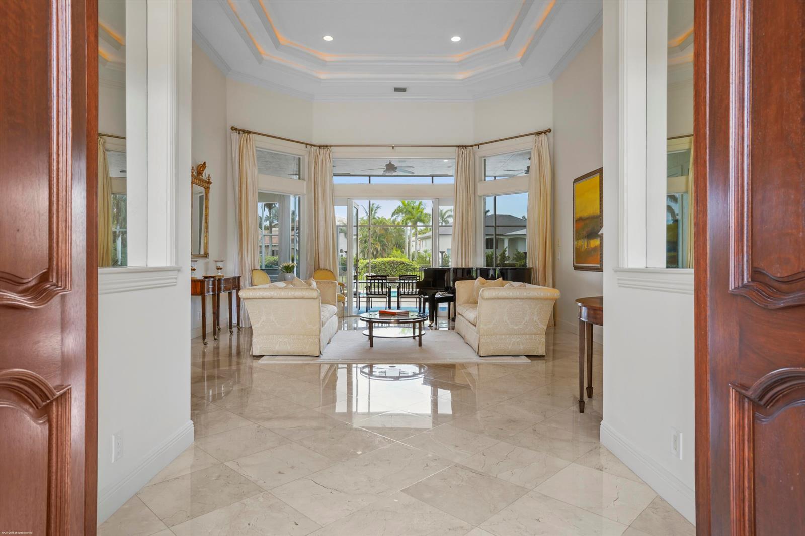 A formal living room features marble floors, a tray ceiling, and a view of a pool — 12809 Mizner Way, Wellington FL 33414, WELLINGTON, FL