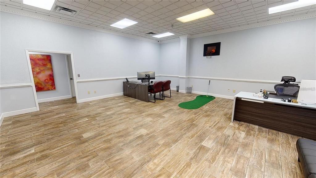 An office space features wood-look tile flooring, two desks, a basketball hoop, and a putting green — 109 COMMERCE STREET UNIT 109, LAKE MARY, FL