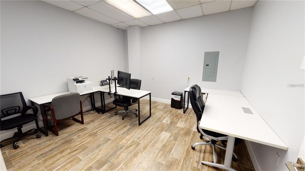 An office space features white desks, rolling chairs, wood-look tile flooring, and a drop ceiling — 109 COMMERCE STREET UNIT 109, LAKE MARY, FL