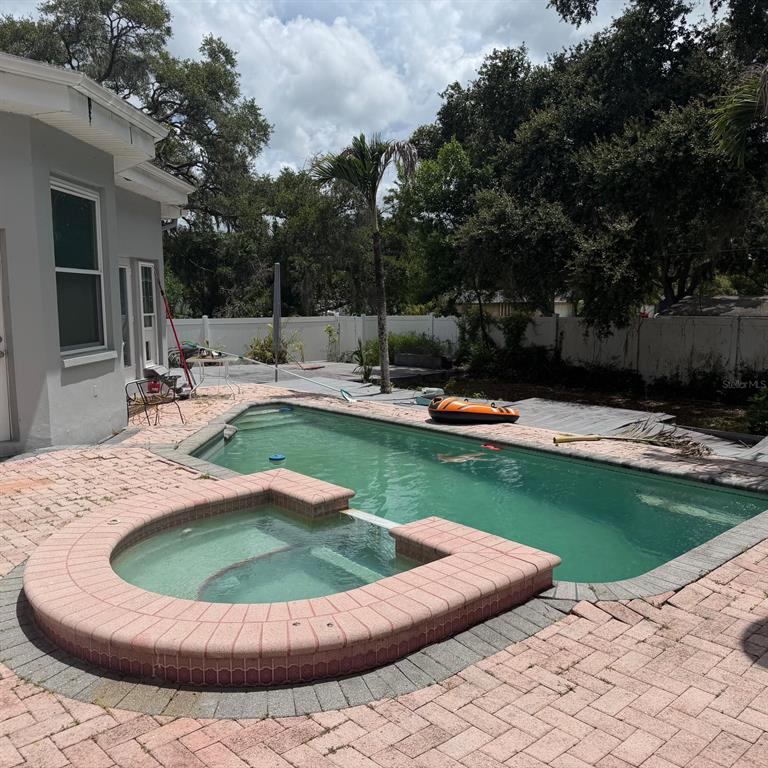 A backyard features a swimming pool, an attached hot tub, and brick paver decking — 1931 OAK RIDGE COURT, CLEARWATER, FL